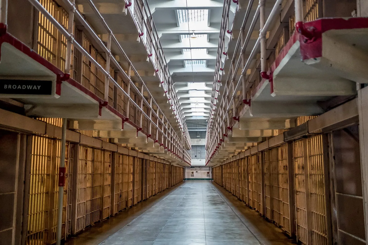 A corridor extends between two rows and three tiers of cells. Skylights let in light from overhead.