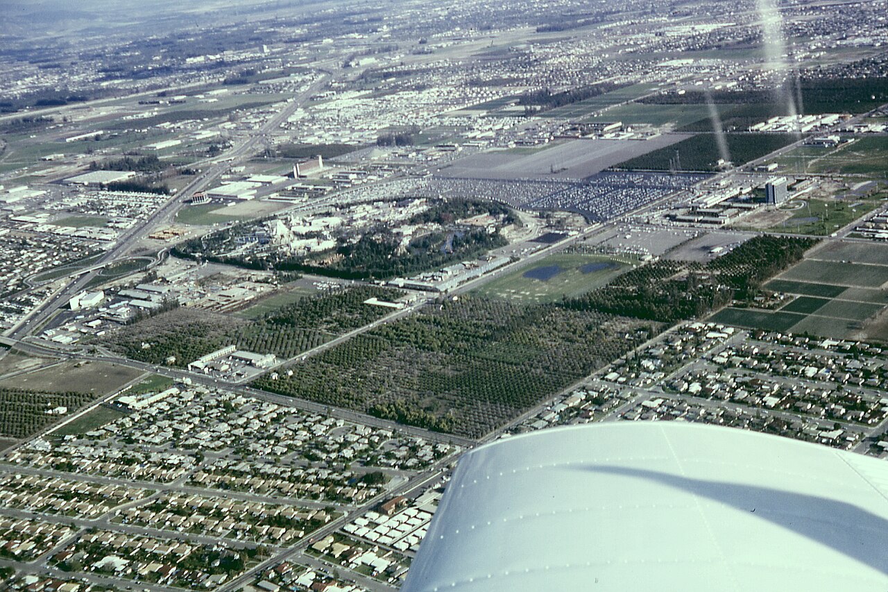 Archival aerial photo of Anaheim, California including Disneyland, the Disneyland Hotel, and the monorail system. The Disneyland Heliport, surrounding orange groves, Santa Ana Free